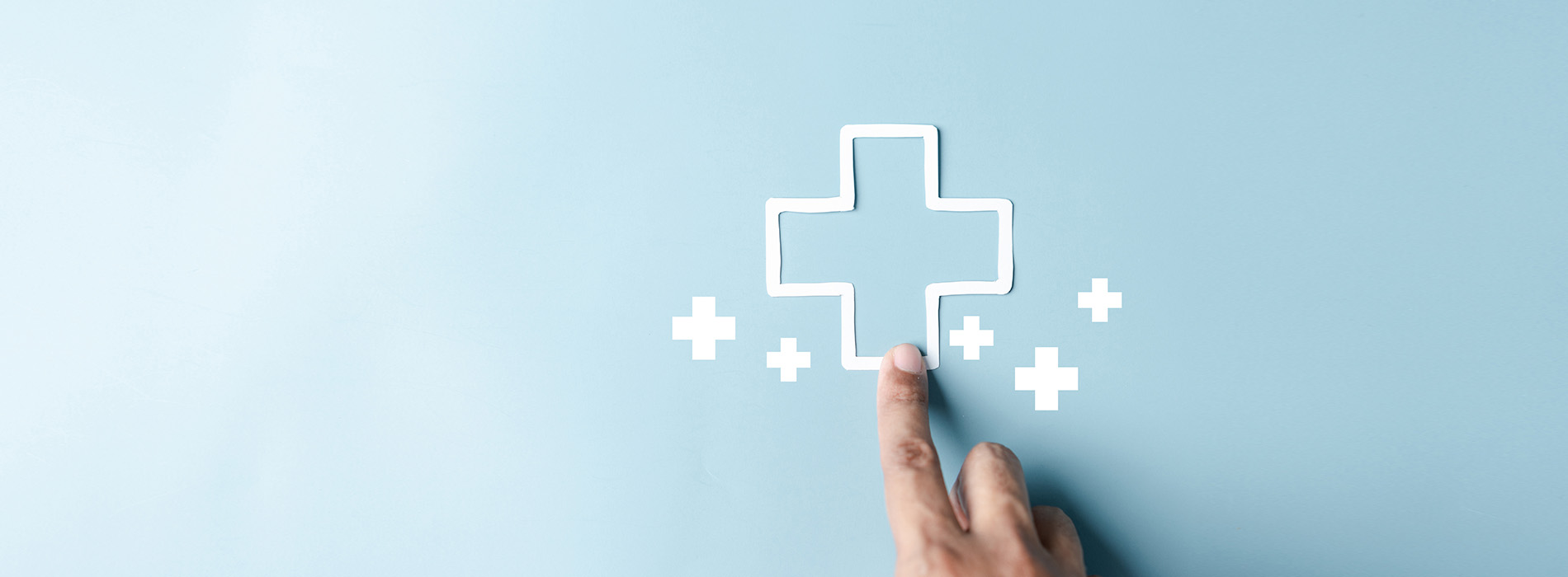 The image shows a close-up view of a hand holding a smartphone with a medical cross symbol displayed on the screen, suggesting healthcare or medical information being accessed.