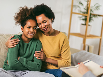 A heartwarming scene of a mother and child sharing a moment on a couch, with the mother holding her child close.